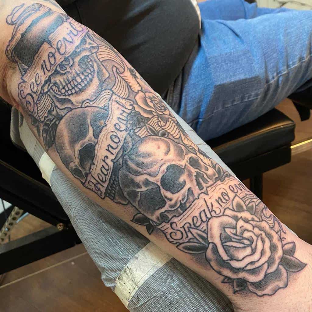 Arm tattoo featuring a skull with "See no evil, Hear no evil, Speak no evil" and a rose design