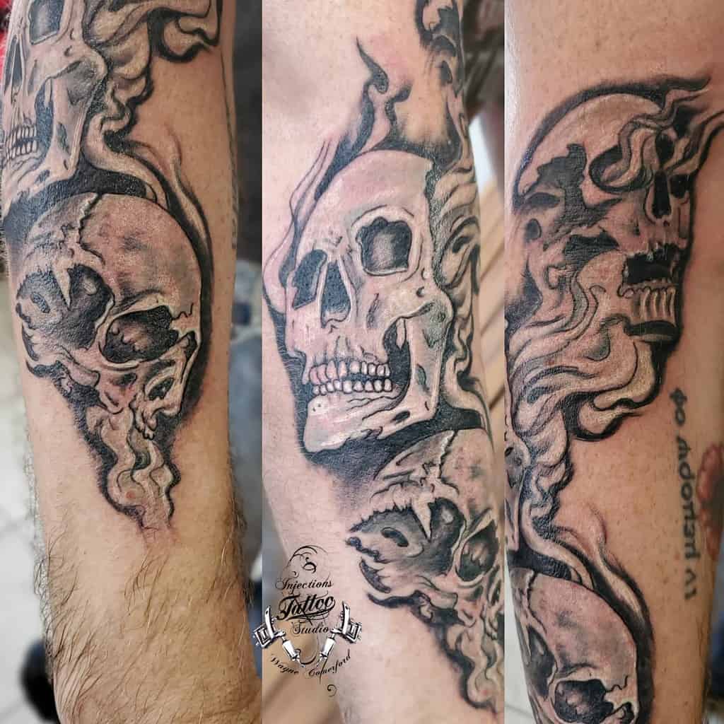 Dark, shaded tattoo of three melting skulls on a forearm, symbolizing 'Hear No Evil, See No Evil, Speak No Evil,' with smoke-like detailing