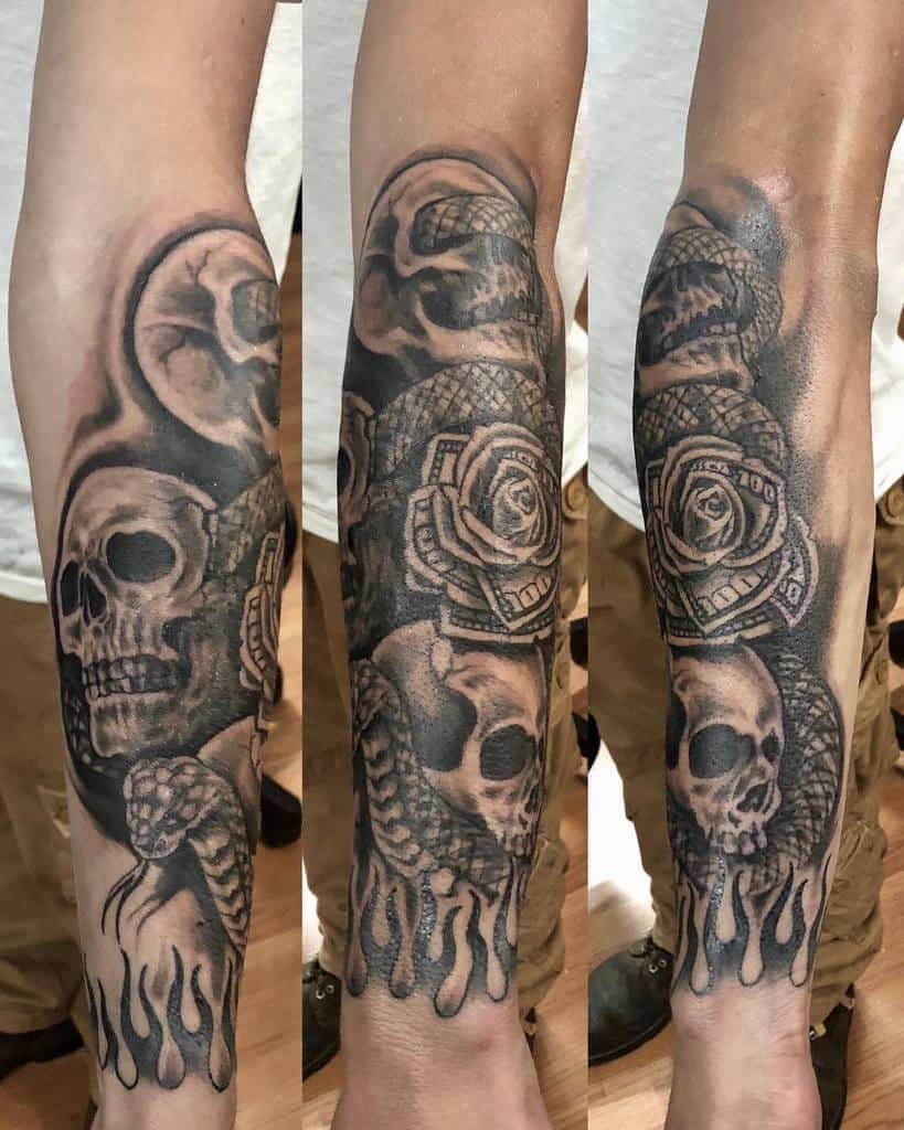 Forearm tattoo featuring a skull, roses, playing cards, a snake, and flames in black and gray ink