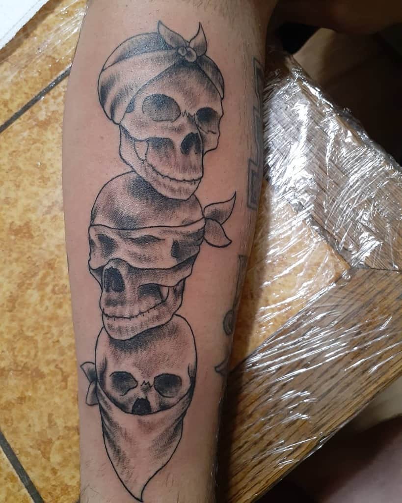 Tattoo of three stacked skulls wearing bandanas, each representing 'Hear No Evil, See No Evil, Speak No Evil,' with shaded black and gray detailing