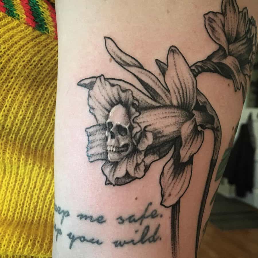 A striking tattoo featuring a daffodil with a skull subtly embedded in the flower's center, blending beauty and the macabre with intricate shading.