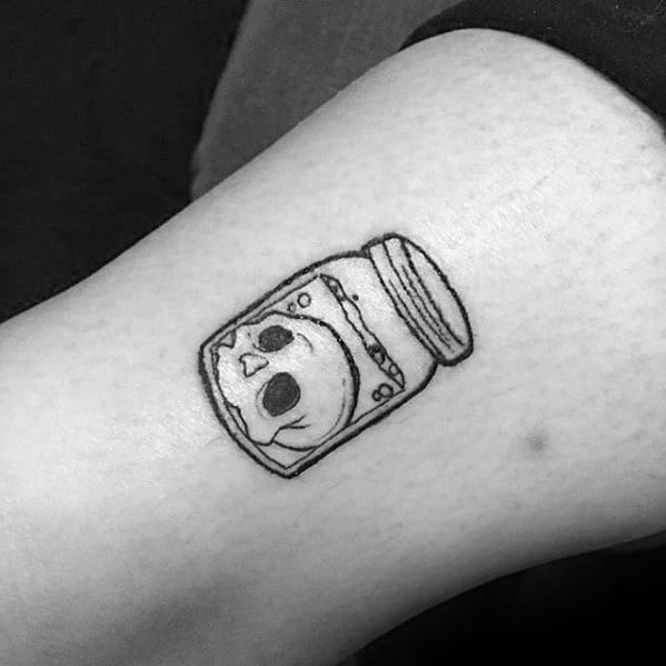 Tattoo of a skull inside a jar on an arm