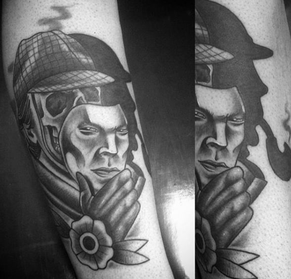 Tattoo of Sherlock Holmes with a deerstalker hat, pipe, floral detail, and a mask being removed, in black and gray style