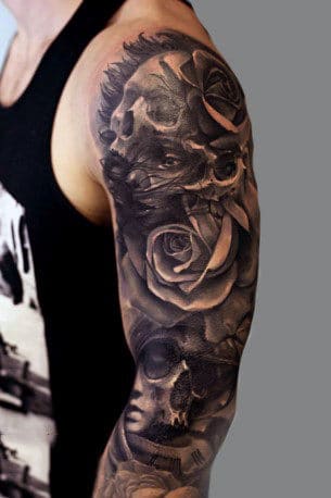 Arm sleeve tattoo featuring skulls and roses in black and gray ink