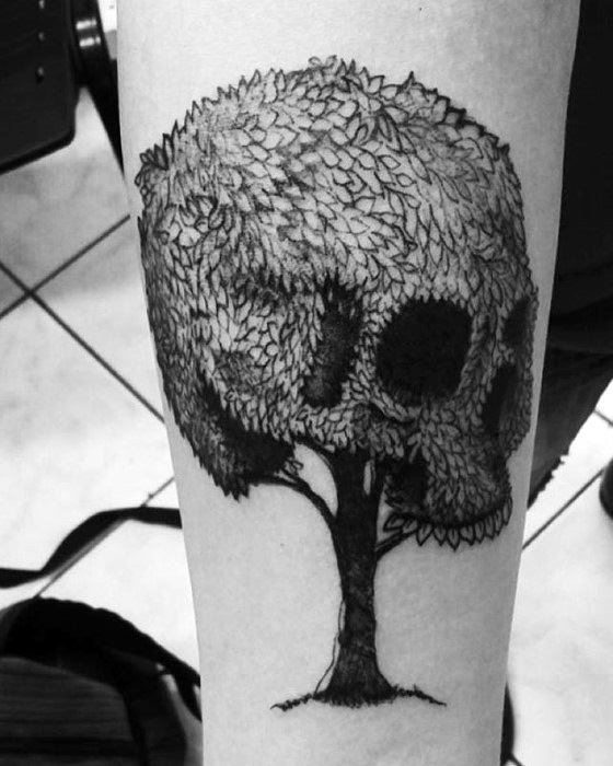 Tattoo of a tree with foliage forming the shape of a skull on someone's arm