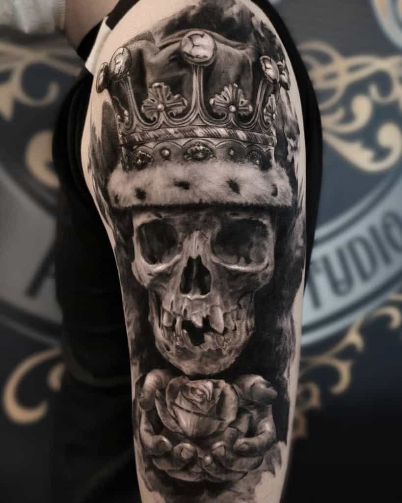 Tattoo of a crowned skull holding a rose on an upper arm