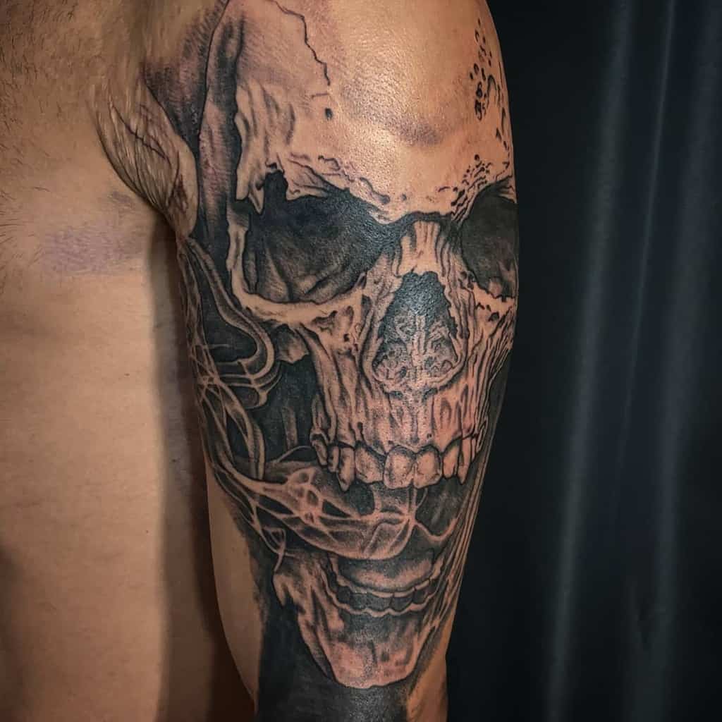 Tattoo of a detailed, dark skull on a man's upper arm 
