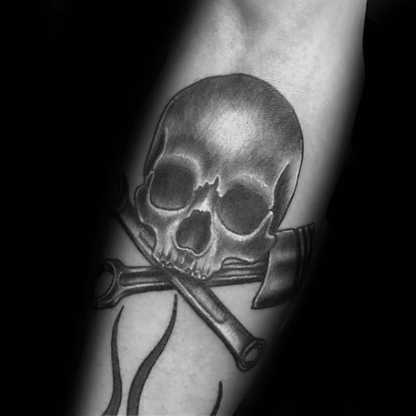 Black and grey tattoo of a skull above two crossed wrenches, mimicking a pirate-style design with a mechanical twist.