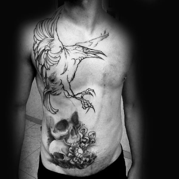 Skulls With Flying Crow Tattoo On Mans Chest