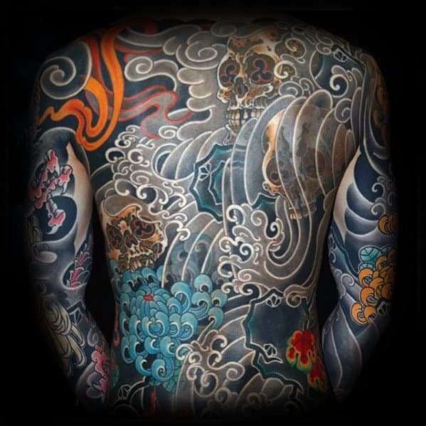 Traditional Japanese full-back tattoo featuring skulls, ocean waves, vibrant chrysanthemums, and fiery accents