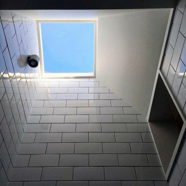 Bathroom ceiling with a skylight window bringing in natural light, surrounded by white subway tiles.
