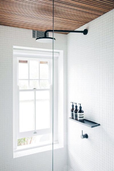 Contemporary shower with modern wood panel ceiling, white tile walls, and black fixtures.
