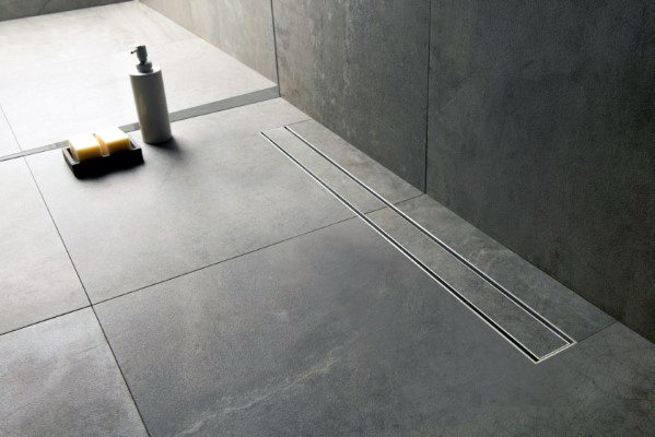 Slate bathroom floor tiles with linear drain and minimal design.