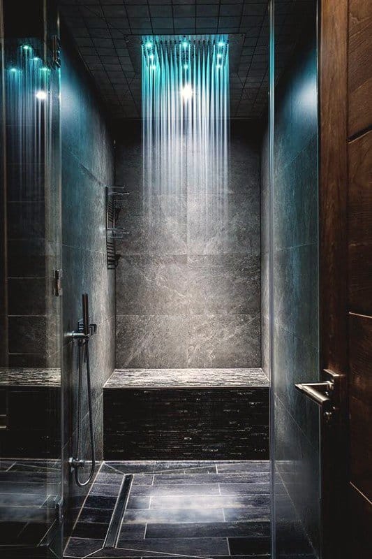 Luxurious shower with dark slate tiles, rainfall LED showerhead, and built-in stone bench.