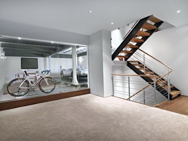 Modern floating stairs with metal and wood design next to a glass-enclosed garage in a sleek basement.