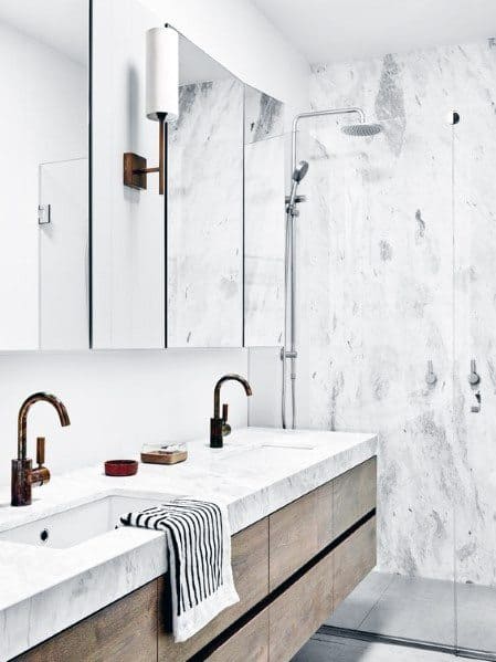 Sleek floating vanity with wood finish, marble countertop, and wall-mounted faucets.