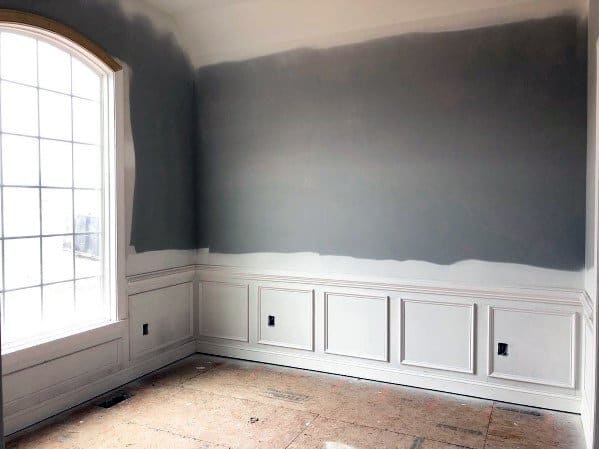 Room with partially painted gray walls, large window, and white wainscoting with chair rail on lower walls