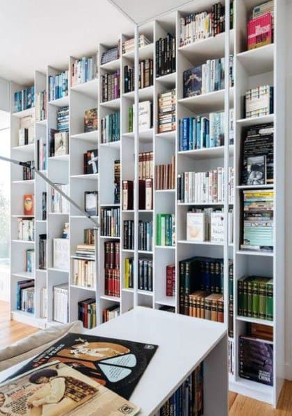 A bright, modern library room boasts tall white bookshelves brimming with diverse reads