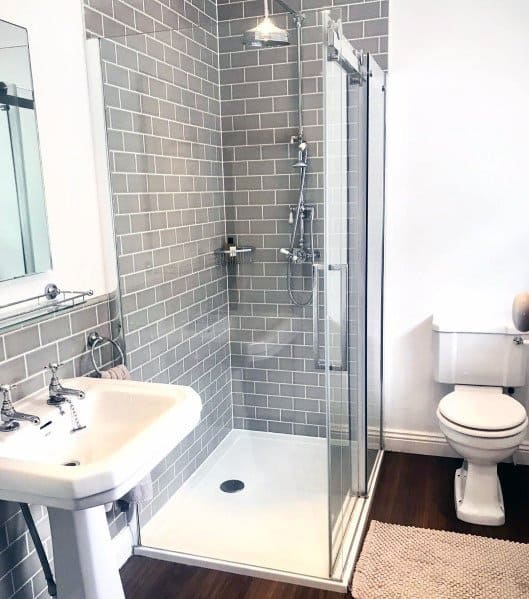 Modern bathroom with glass shower, grey and white sink, and toilet on wooden floor
