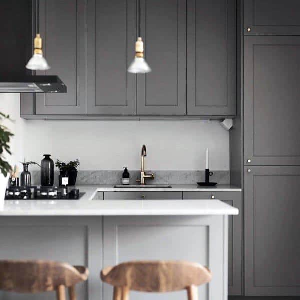 Sleek grey kitchen featuring paneled cabinets, a white countertop, and brass accents for a modern touch.