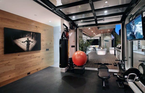 Stylish home gym with rubber flooring, punching bag, exercise ball, and retractable glass garage door.
