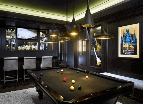 Sleek billiard room with black felt table, modern pendant lighting, and a stylish bar area.