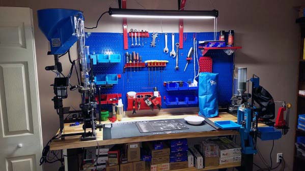 Sleek and well-organized reloading bench with a vibrant blue pegboard, neatly arranged tools, reloading presses, ample lighting, and efficient under-bench storage for supplies