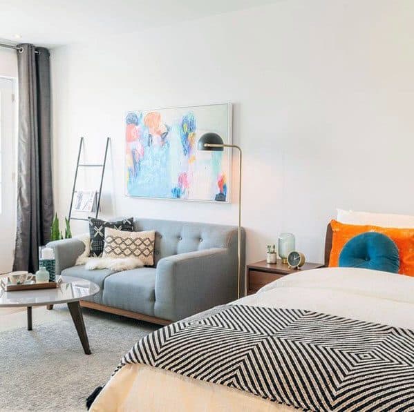 A vibrant studio with a gray sofa, bold art, and cozy accents.