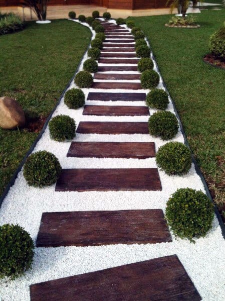 Garden walkway with wooden steps, bordered by small round bushes and white gravel