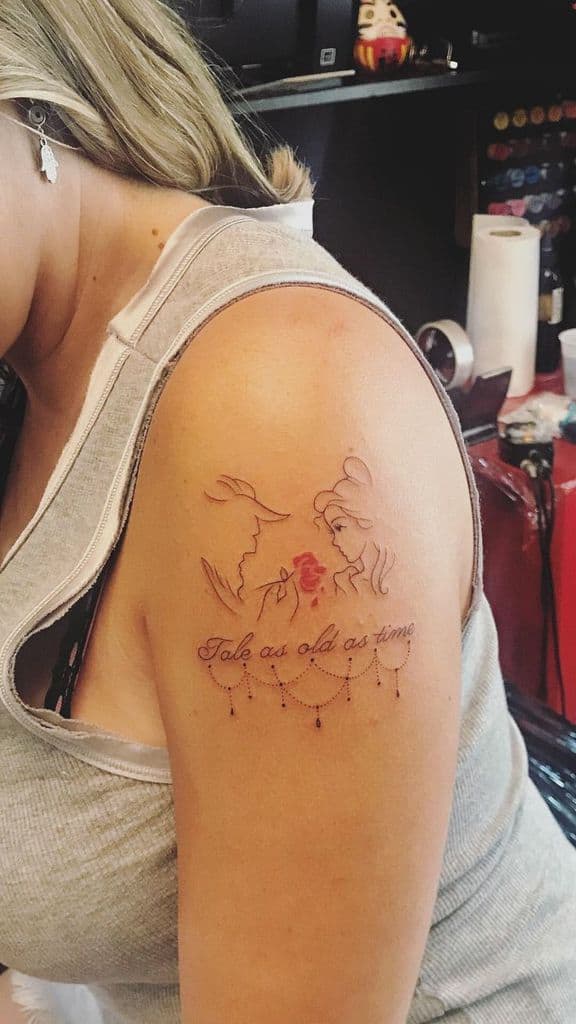 Minimalist fine-line tattoo of Belle and the Beast with a red enchanted rose, accompanied by 'Tale as old as time' in elegant script and decorative details.