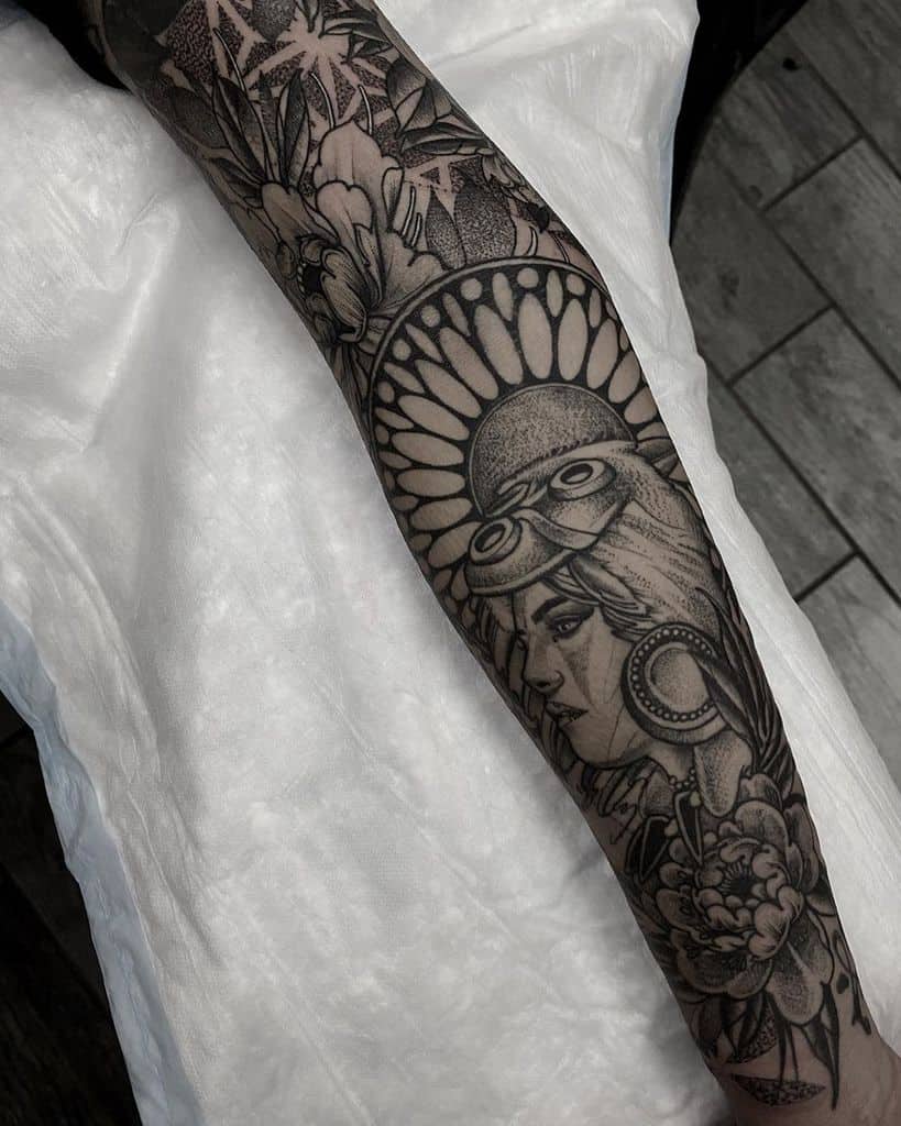Black and grey full-sleeve tattoo featuring a stylized portrait of San with her wolf mask, intricate floral patterns, and bold shading.
