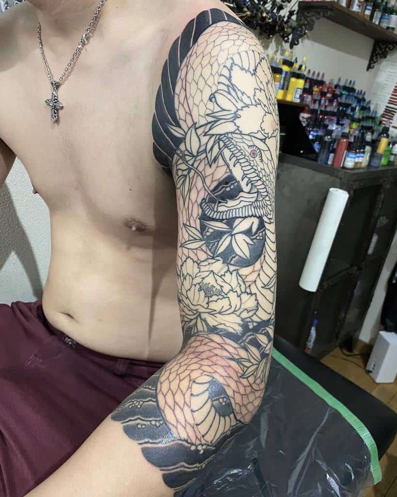 A man with an intricate snake and floral tattoo sleeve on his right arm