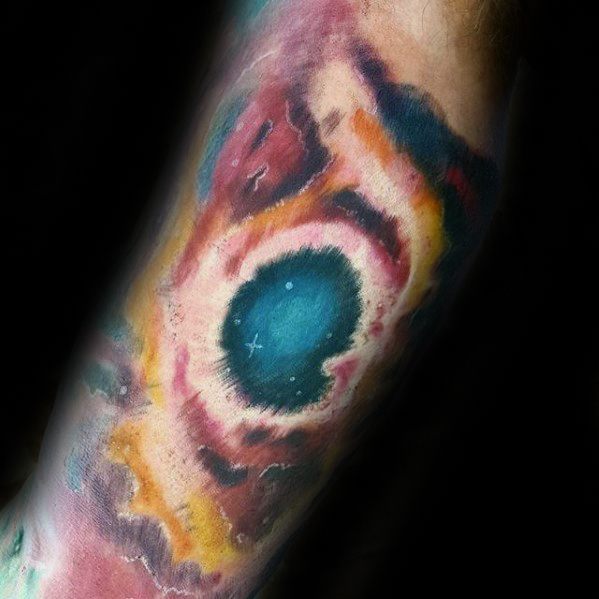 Vibrant nebula tattoo with a central blue sphere gracing the forearm