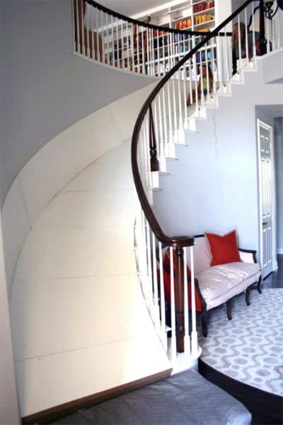 A spiral staircase features a built-in slide beside a cozy sofa in the modern interior