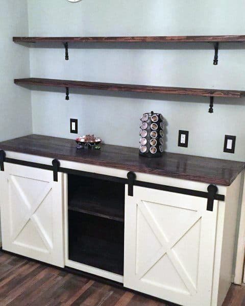 Sliding barn door cabinet with rustic shelves, coffee pod holder, and light blue wall.