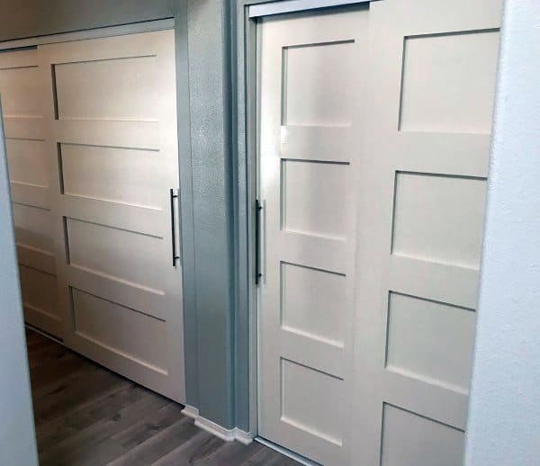 White paneled sliding closet doors with metal handles complement the gray walls and wood flooring