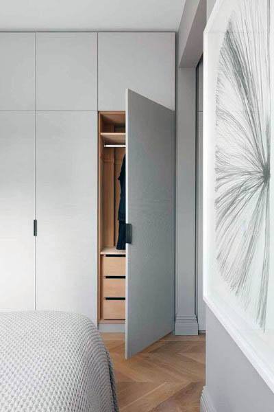 A minimalist bedroom with a sleek sliding closet door, featuring a neutral gray finish and a clean, modern design