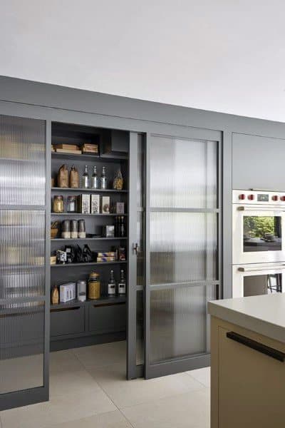 Modern kitchen pantry with sliding frosted glass doors and organized shelving.