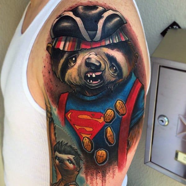 Colorful tattoo of Sloth from *The Goonies* reimagined as a raccoon, wearing a Superman shirt, pirate hat, and surrounded by gold coins.