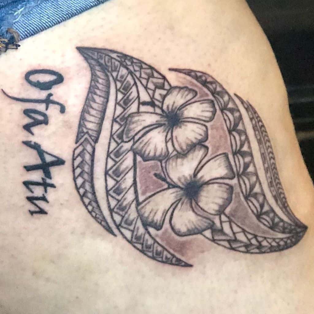 Tattoo with plumeria flowers and tribal patterns, with the text "Ofa Atu" on the side