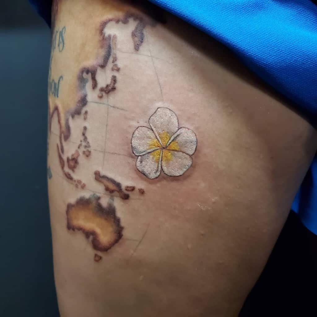 Tattoo of a world map intertwined with a plumeria flower