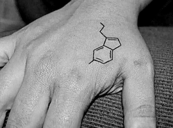 A tattoo of serotonin's chemical structure elegantly graces a person's hand, symbolizing joy and balance in their life