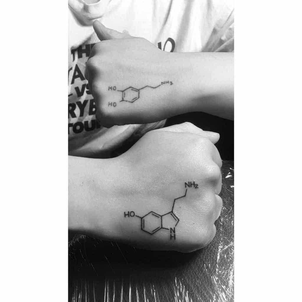 Two hands adorned with intricate serotonin molecule tattoos