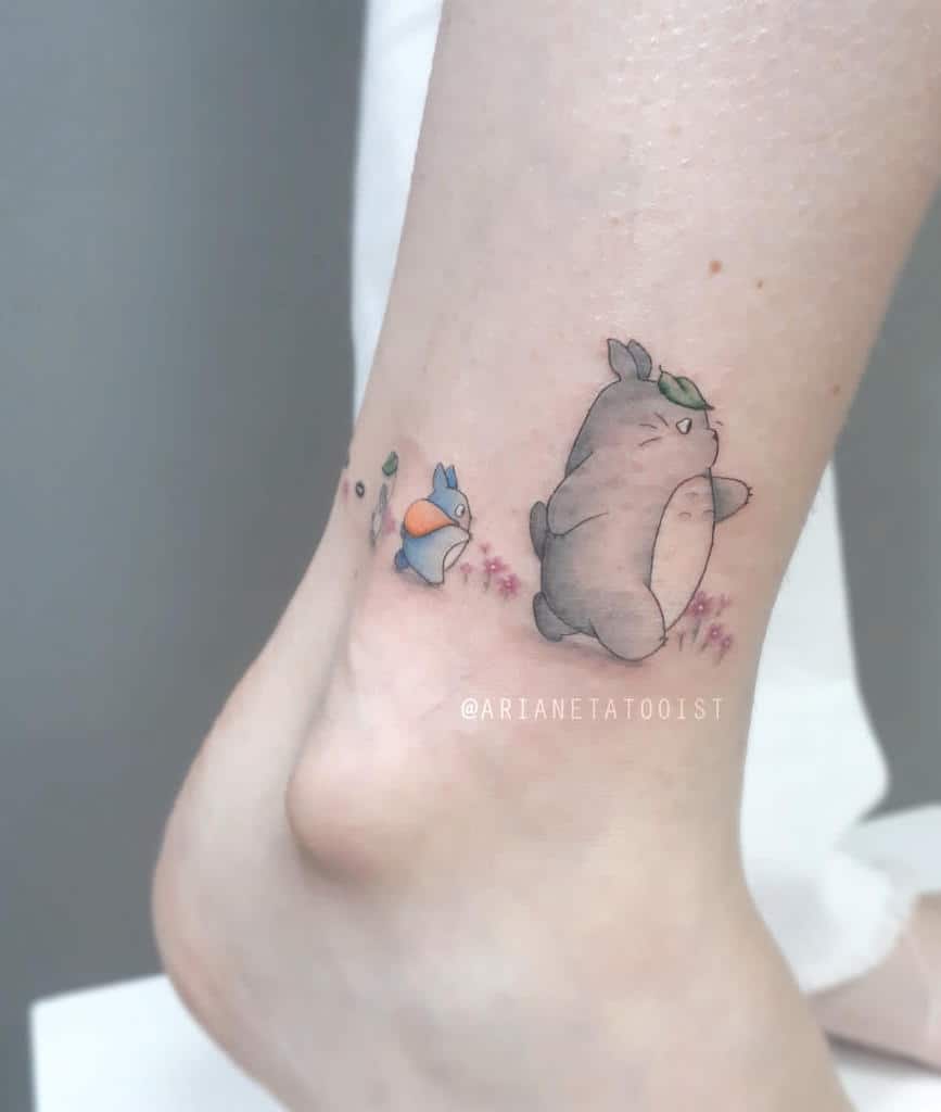 A cute minimalist Totoro tattoo on the ankle, featuring Totoro and his smaller companions, perfect for subtle Studio Ghibli fans