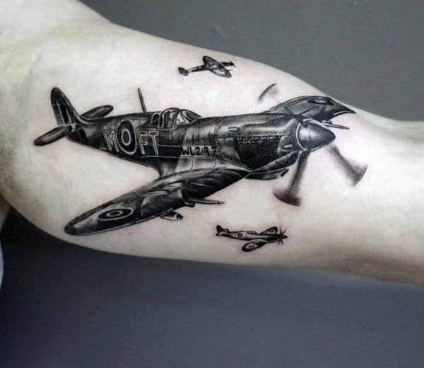 Tattoo of three WWII airplanes flying on an upper arm with a gray background