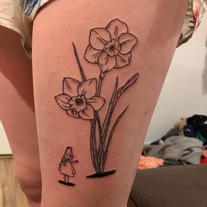 A whimsical tattoo featuring two large daffodils alongside a small figure, adding a sense of scale and enchantment to the floral design with minimalist black ink.