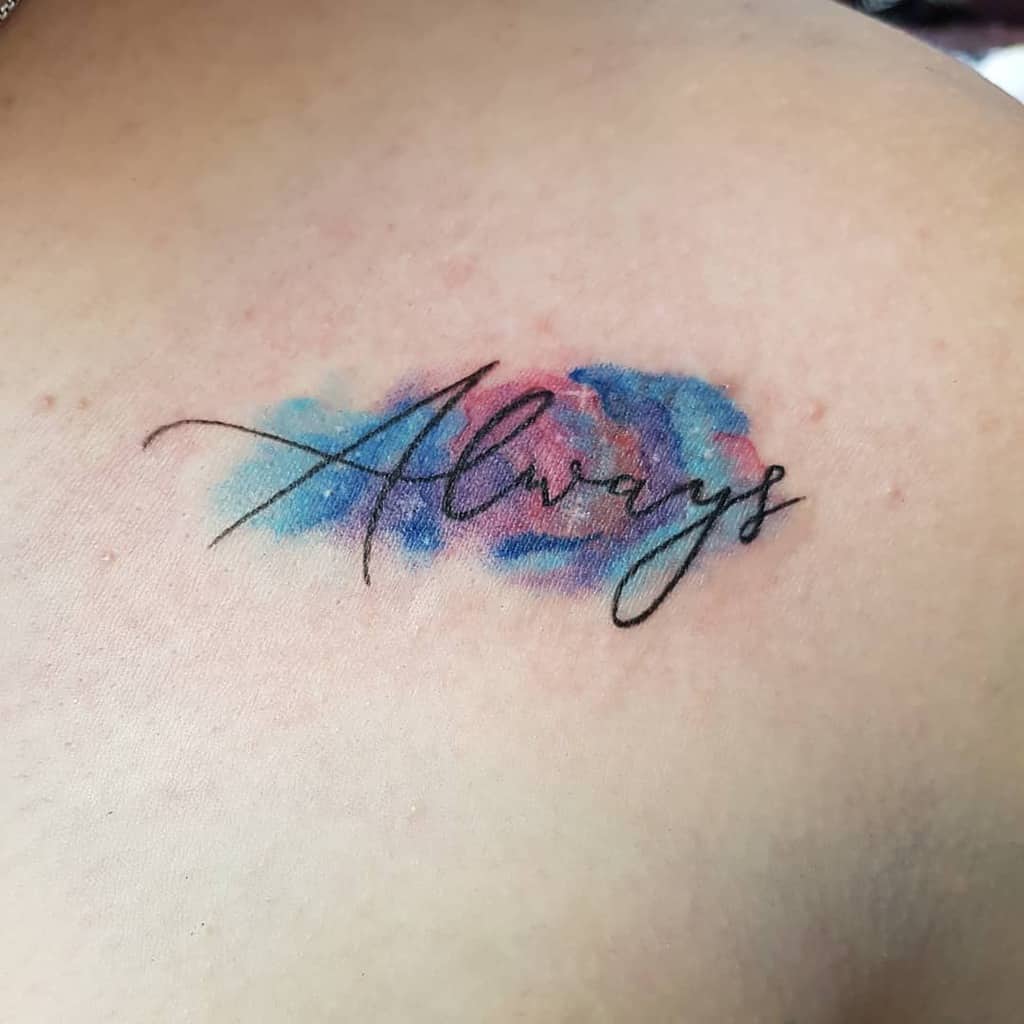 Watercolor tattoo of the word "Always" in cursive, surrounded by splashes of blue and pink