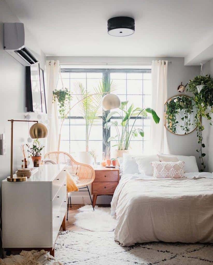 Cozy bedroom with large window, plants, rattan chair, and light neutral decor.