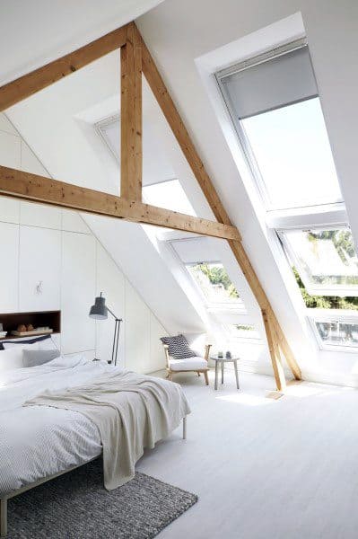 Bright attic loft bedroom with large skylight windows, wooden beams, and minimalist decor