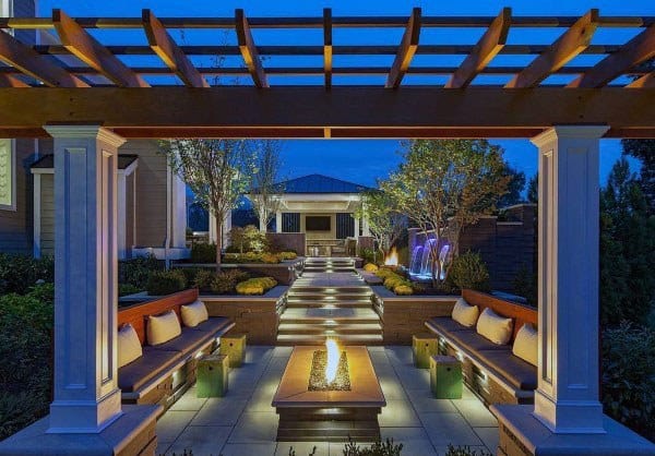 Modern pavilion with built-in seating, a central firepit, and illuminated pathways, creating a vibrant outdoor lounge.
